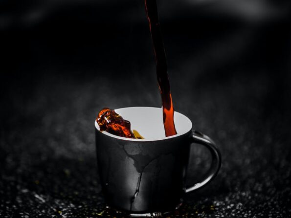 brown liquid pouring on black and white ceramic mug selective color photography