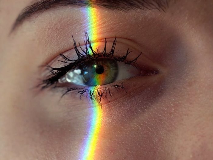 anonymous woman with rainbow light on face