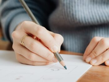 crop unrecognizable female designer drawing on paper in office