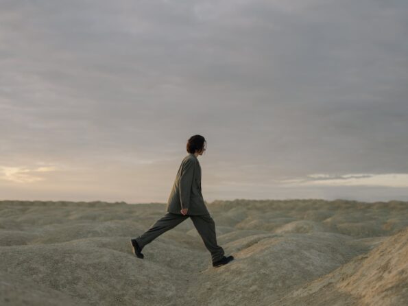 man in white long sleeve shirt and black pants walking on gray sand