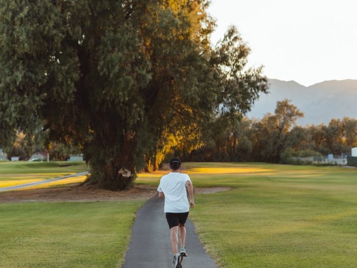 unrecognizable woman jogging along footpath in park