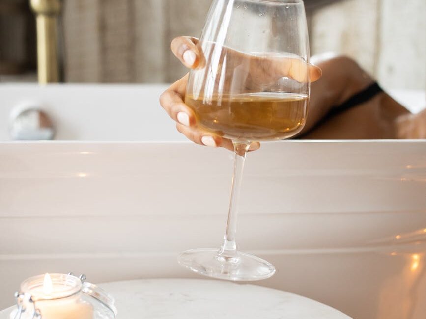 woman taking wineglass from round table in bathroom